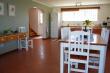 Open plan dining room between fully equipped kitchen and outdoor braai under roof. 
